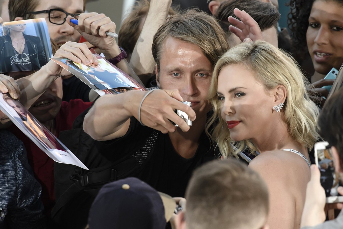 epa06093332 South African actress and cast member Charlize Theron (R) takes selfies with fans during the film premiere of 'Atomic Blonde' at the Theater am Potsdamer Platz in Berlin, Germany, 17 July 2017. The movie opens across German theaters on 24 August. EPA/CLEMENS BILAN
